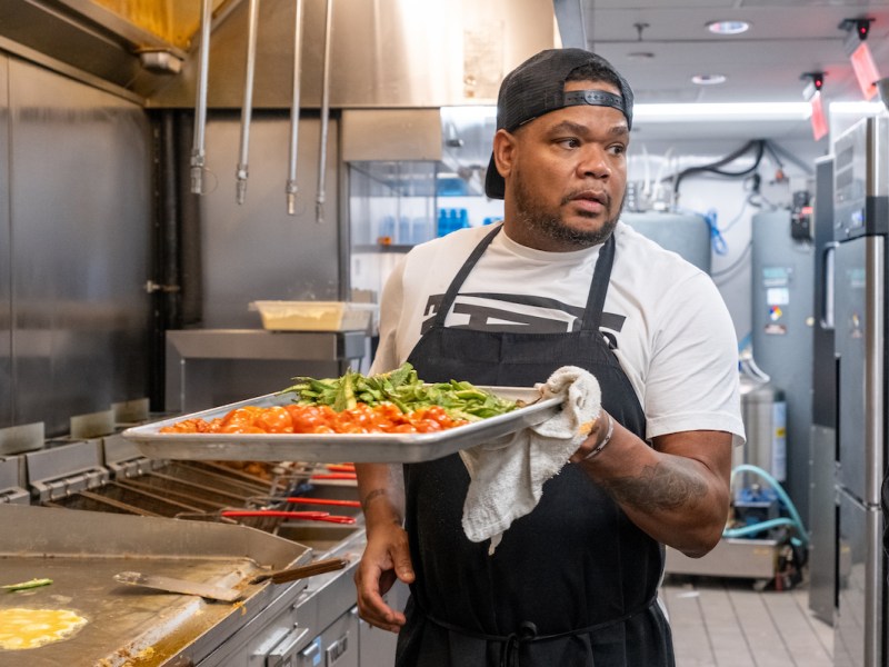 Sammy Davis Jr., chef consultant with Thompson Hospitality, stands in the kitchen at Milk & Honey's SW Wharf location, preparing vegetables for serving. (Ja’Mon Jackson/The Washington Informer)