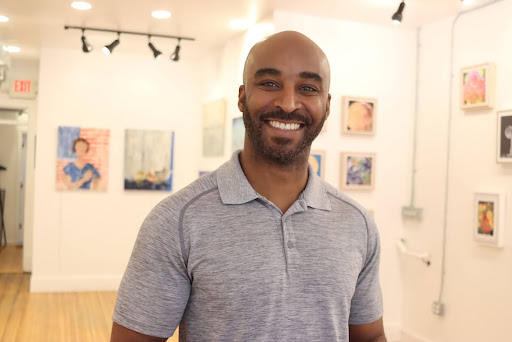 Chidi Ononuju stands in front of diverse art in Washington, D.C., at Africa World Art Gallery on May 14, 2024. (Eden Harris/The Washington Informer)