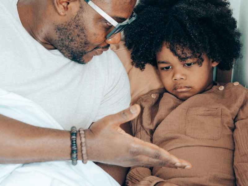 black father speaking with child at home