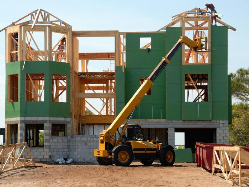 yellow and black heavy equipment near unfinished building