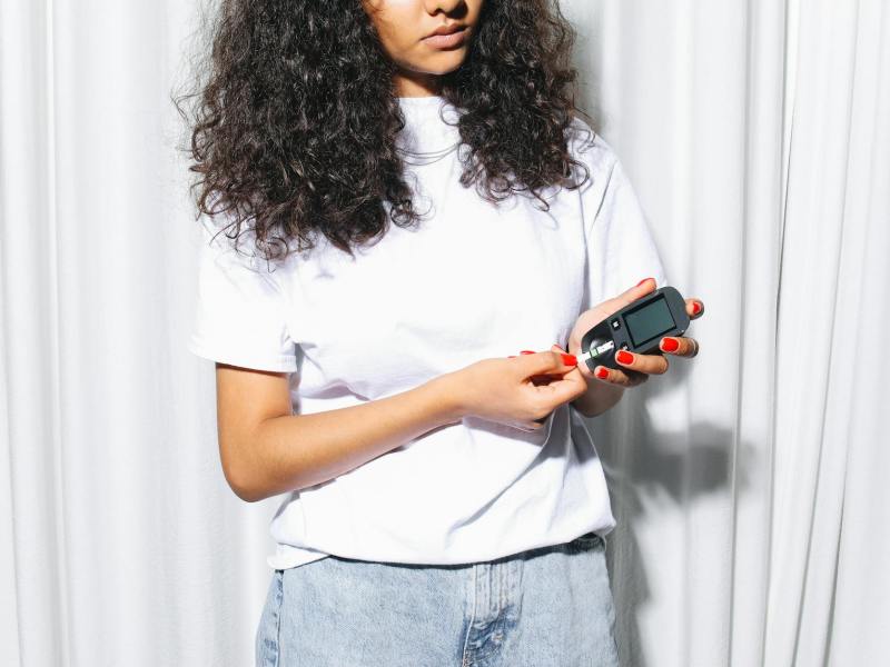 woman in white shirt holding a glucometer