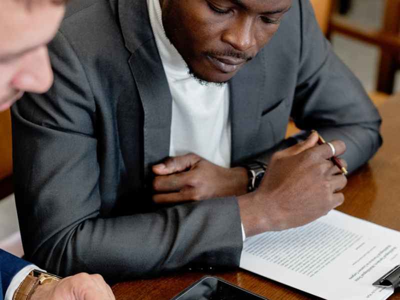 a man in gray suit looking at the tablet on a wooden table